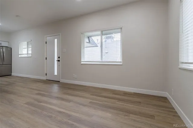 an empty room with wooden floor and windows
