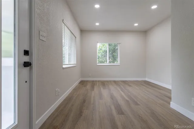 an empty room with wooden floor and windows