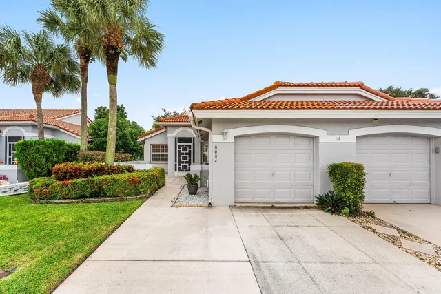a view of a house with a yard plants and palm trees