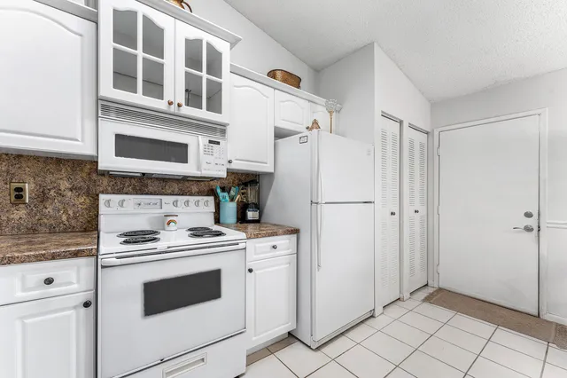 a kitchen with white cabinets and white appliances