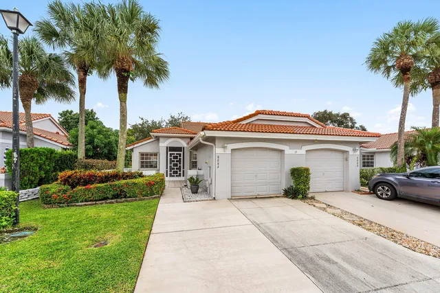 a front view of a house with a garden and palm trees