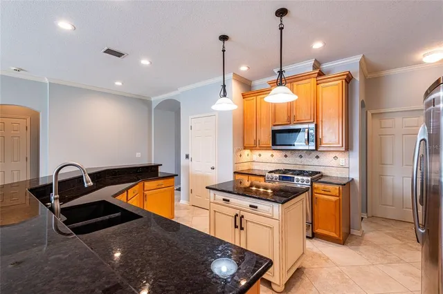 a kitchen with stainless steel appliances granite countertop a sink a stove and a refrigerator