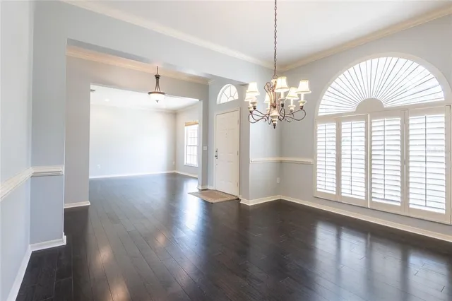 a view of a big room with wooden floor chandelier and windows