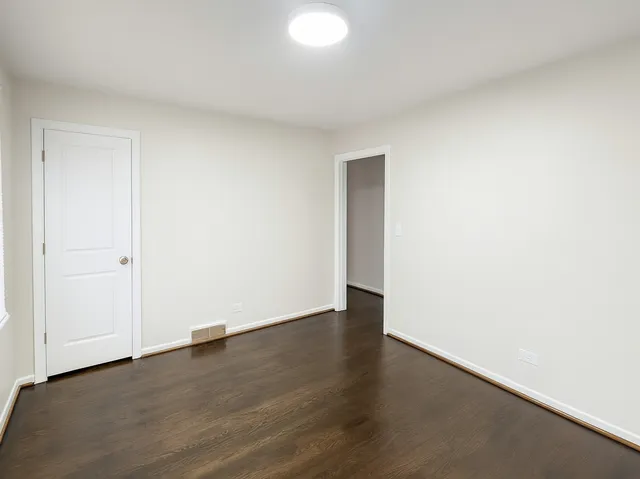 an empty room with wooden floor & windows