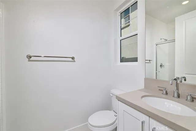 a bathroom with a granite countertop sink mirror vanity and toilet