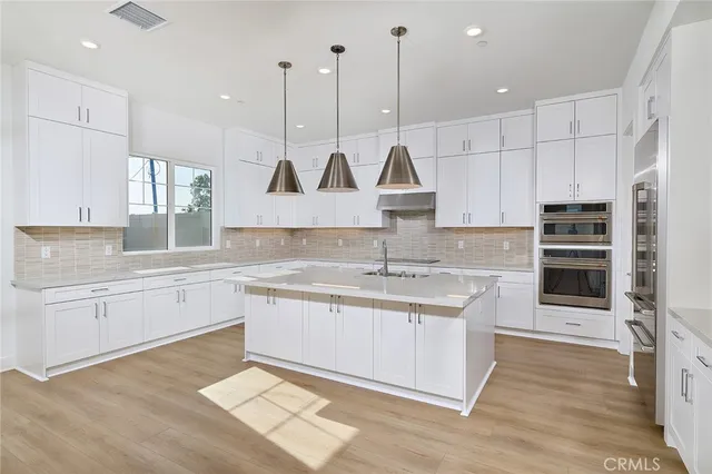 a kitchen with stainless steel appliances granite countertop a sink a stove and a wooden floor