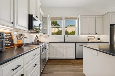 a kitchen with granite countertop cabinets stainless steel appliances a sink and a window