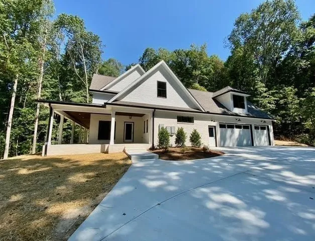 a view of house with backyard and trees in the background
