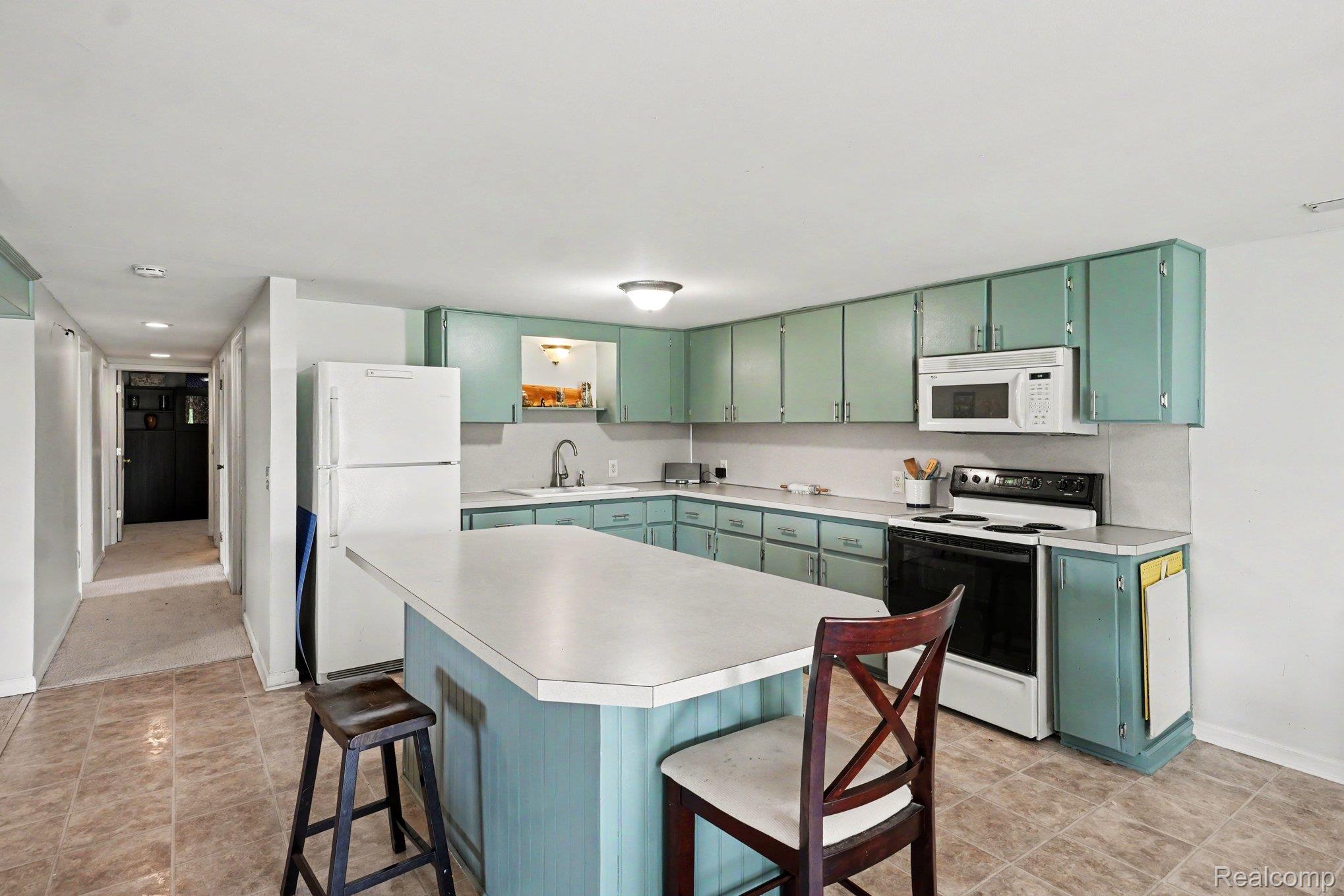 4848 Columbiaville Road Columbiaville, MI 48421 - Photo 20 of 35 Kitchen featuring an island with a breakfast bar, extensive cabinetry, tile flooring, and essential appliances