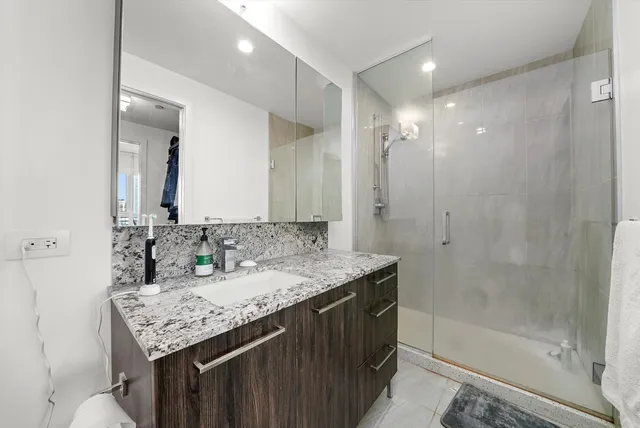 a bathroom with a granite countertop sink a mirror and a shower