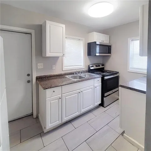 a kitchen with stainless steel appliances granite countertop a stove a sink and a white refrigerator