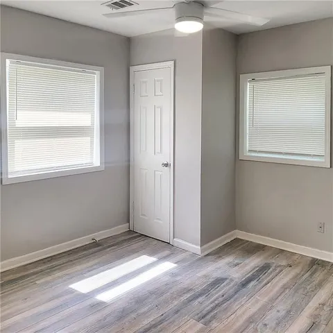 an empty room with wooden floor and windows