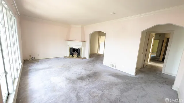 an empty room with windows and fireplace
