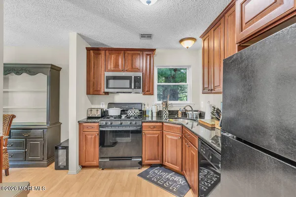 a kitchen with stainless steel appliances granite countertop a stove a sink dishwasher a refrigerator and cabinets with wooden floor