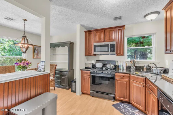 a kitchen with stainless steel appliances granite countertop a stove a sink dishwasher and cabinets with wooden floor