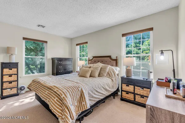 a bedroom with a bed a dresser and a large window