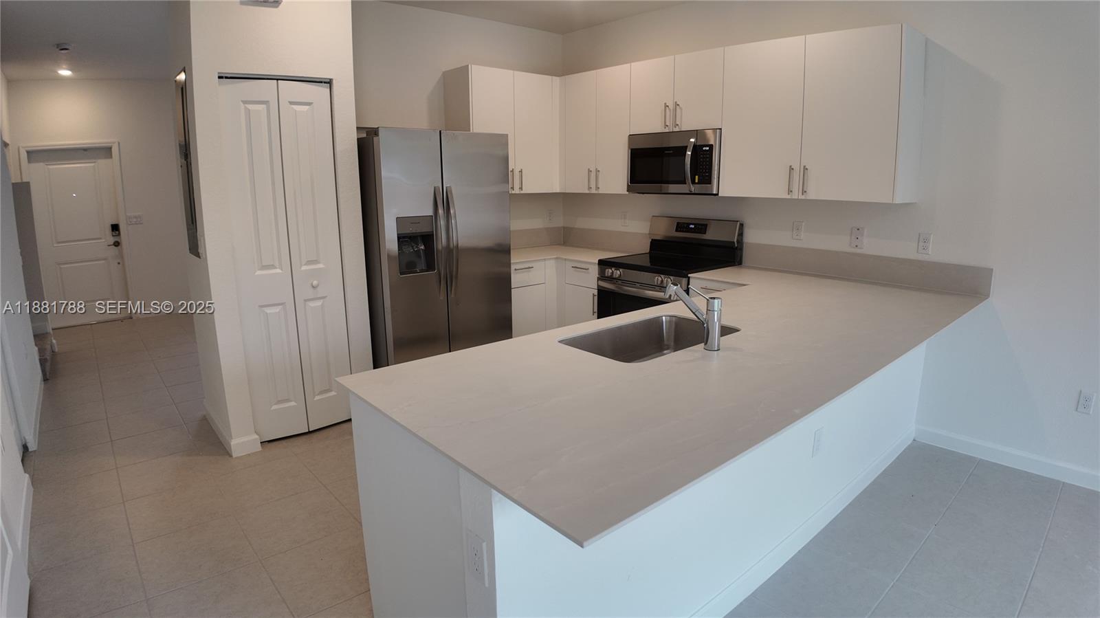 35761 Southwest 178th Court, Unit 35761 Homestead, FL 33034 - Photo 31 of 80 a kitchen with a refrigerator a microwave a sink and cabinets