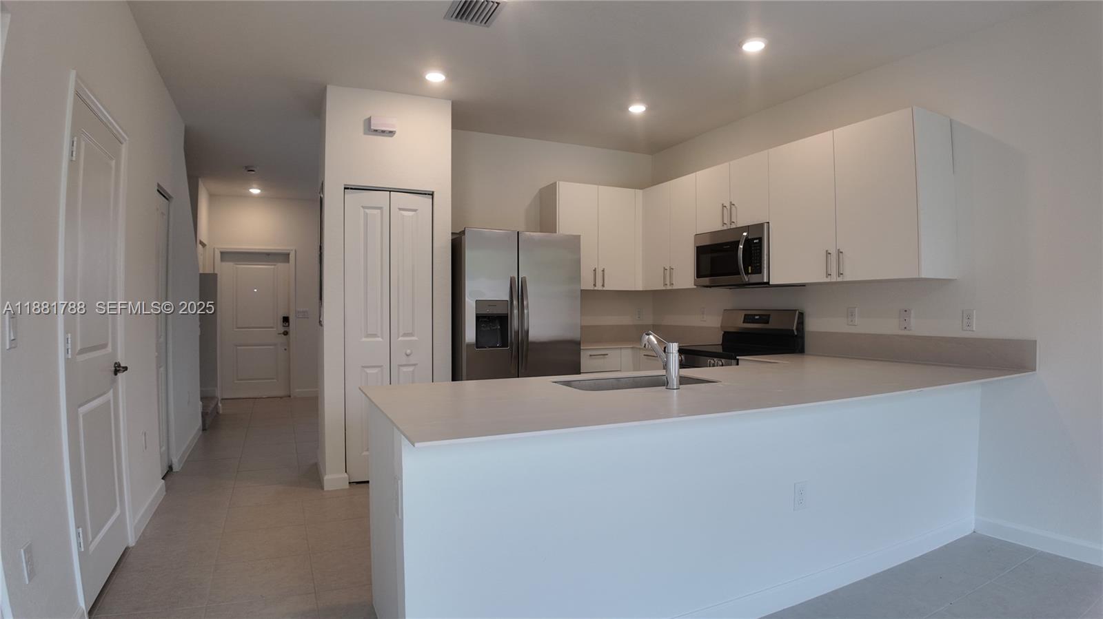 35761 Southwest 178th Court, Unit 35761 Homestead, FL 33034 - Photo 64 of 80 a kitchen with kitchen island granite countertop a refrigerator a sink a stove a microwave and cabinets