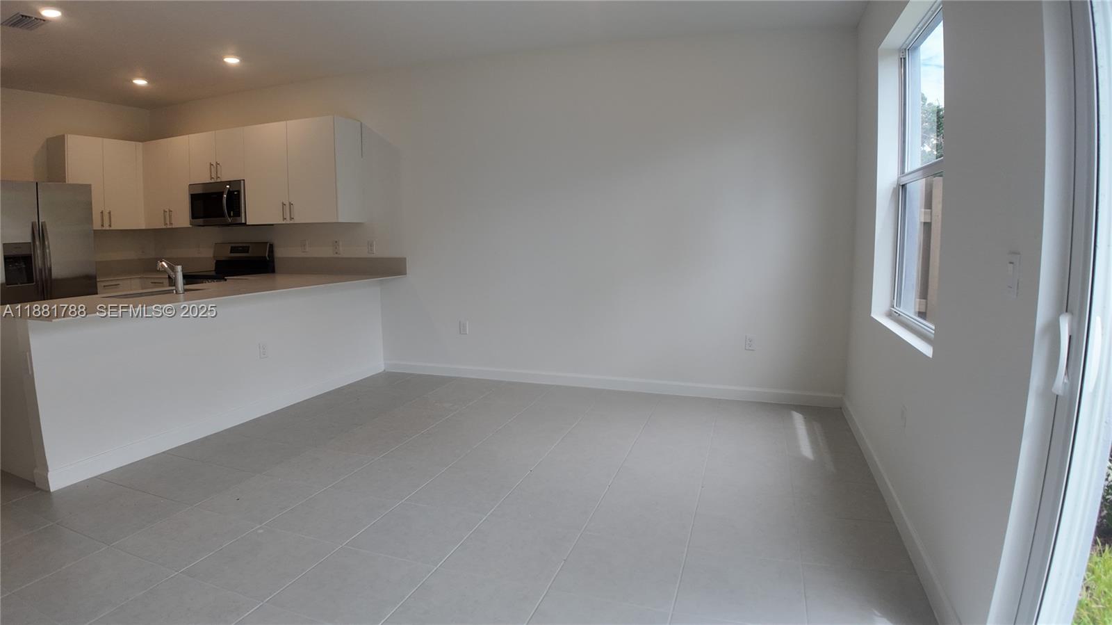 35761 Southwest 178th Court, Unit 35761 Homestead, FL 33034 - Photo 76 of 80 a kitchen with stainless steel appliances a refrigerator a sink a stove a microwave and white cabinets