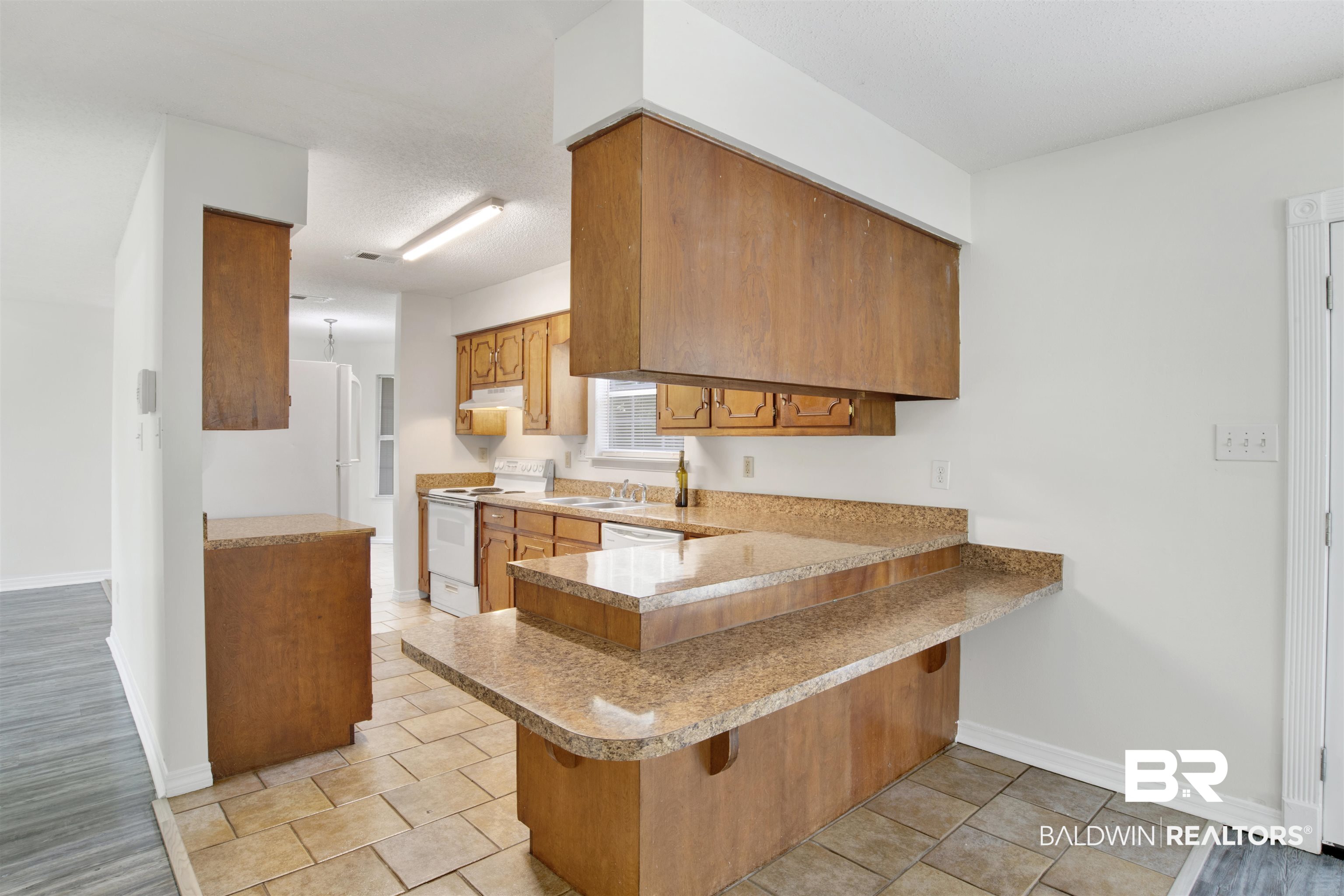 5480 Country Club Boulevard Theodore, AL 36582 - Photo 13 of 36 Kitchen featuring white appliances, a breakfast bar area, kitchen peninsula, and a textured ceiling