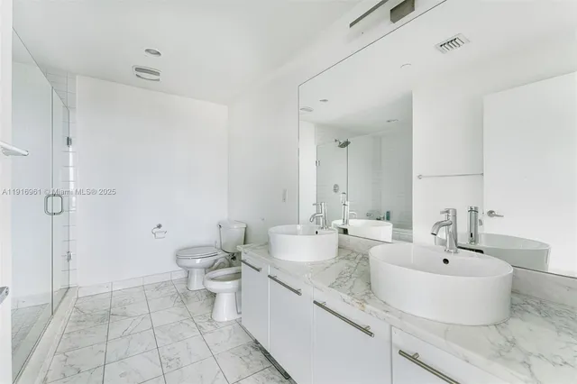 a bathroom with a double vanity sink toilet and a mirror
