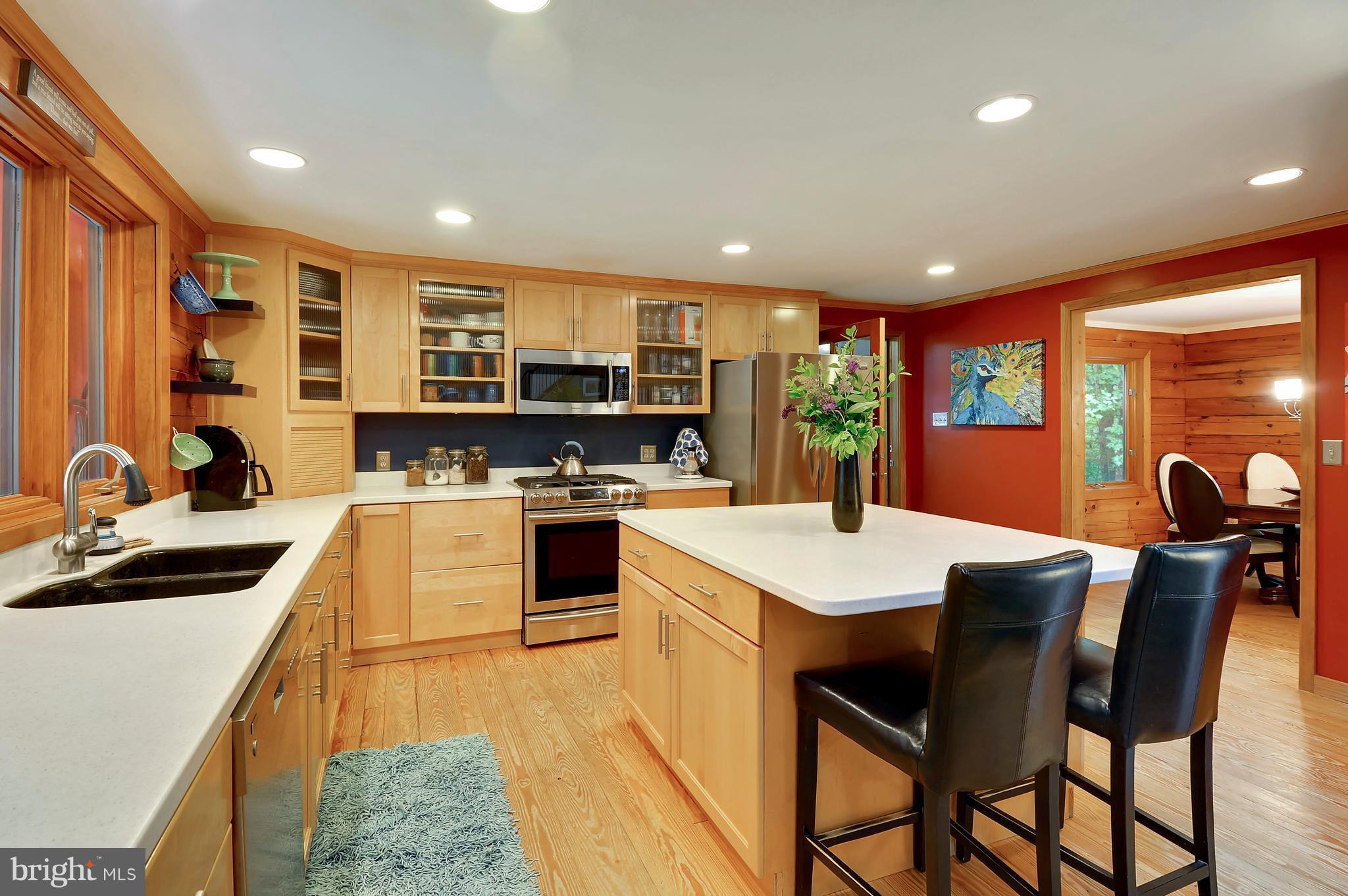 401 Farmington Road West Accokeek, MD 20607 - Photo 4 of 30 a kitchen with stainless steel appliances kitchen island granite countertop a stove a sink a microwave a dining table and chairs with wooden floor