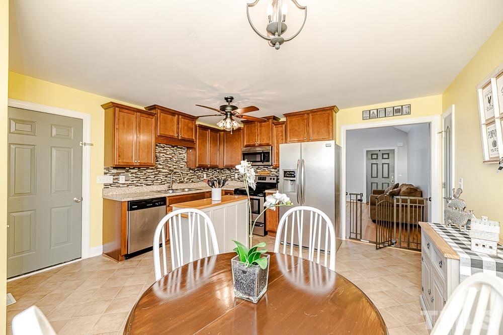 1652 Tingen Road Lillington, NC 27546 - Photo 12 of 30 a kitchen with stainless steel appliances granite countertop a refrigerator a stove a sink dishwasher with a dining table and chairs