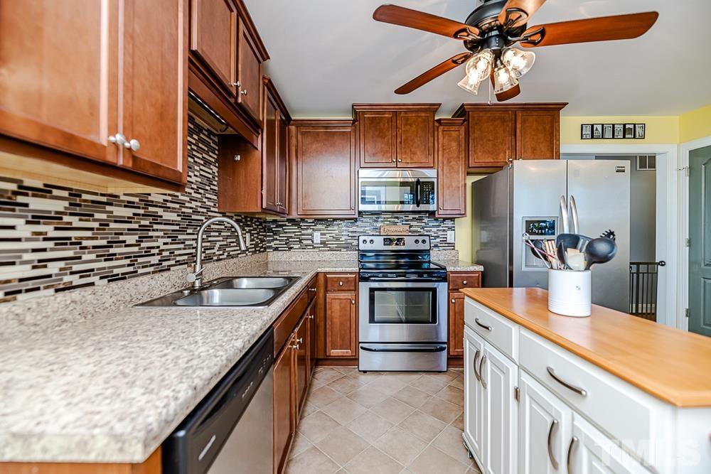 1652 Tingen Road Lillington, NC 27546 - Photo 9 of 30 a kitchen with stainless steel appliances granite countertop a sink a stove and a refrigerator