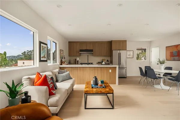 a living room with furniture kitchen view and a large window
