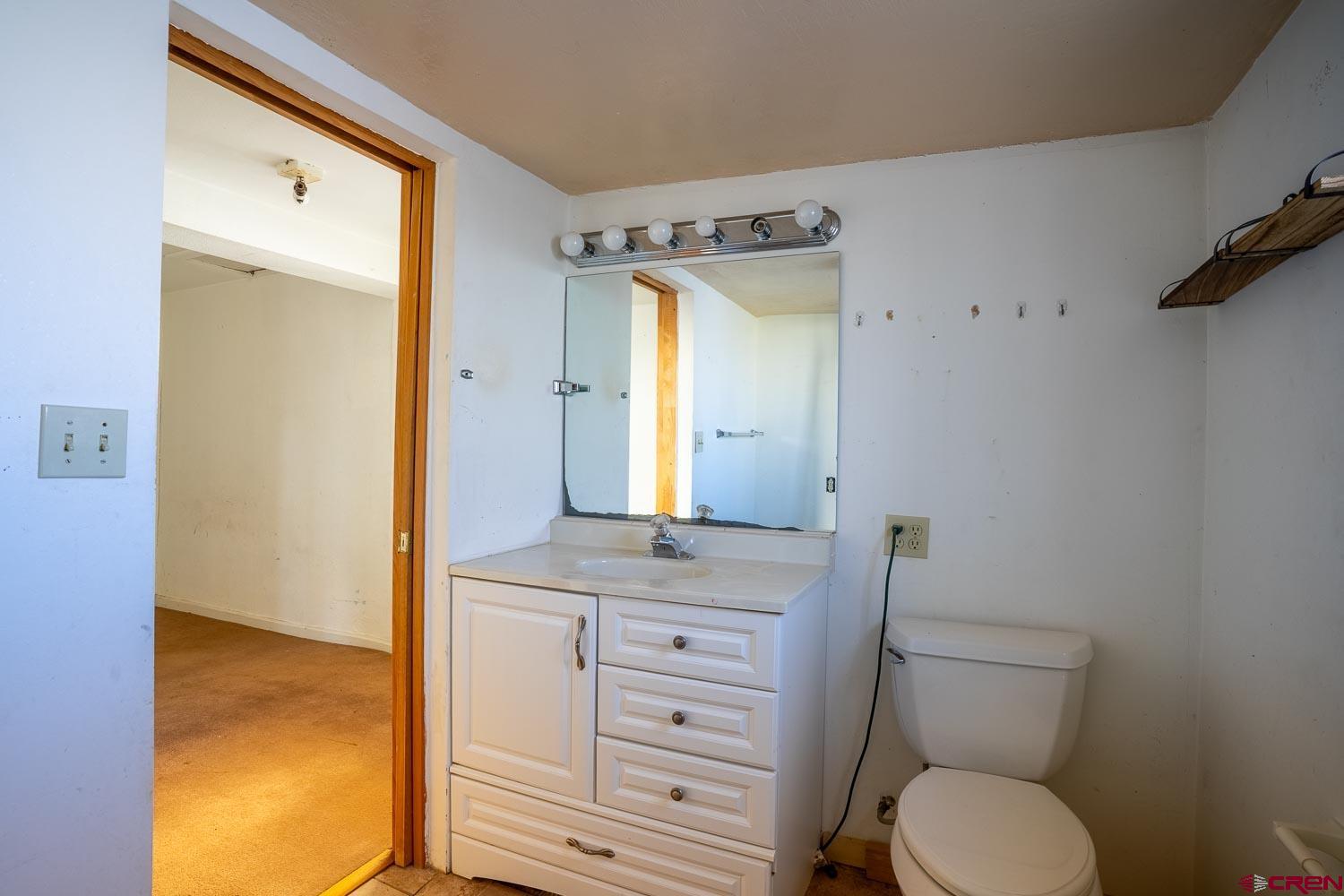 120 Browning Avenue Ignacio, CO 81137 - Photo 19 of 36 a bathroom with a granite countertop toilet sink and mirror