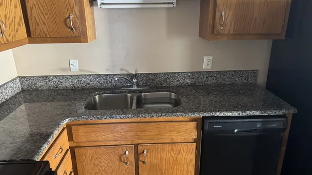 a kitchen with granite countertop a sink stove and cabinets