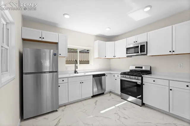 a kitchen with cabinets stainless steel appliances and window