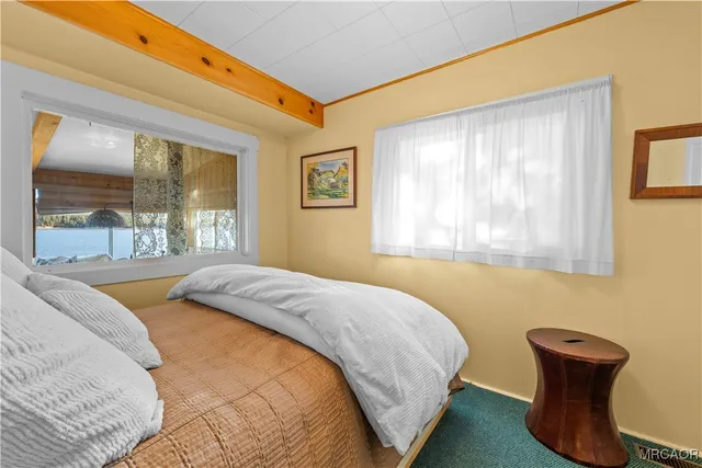 a bedroom with a bed and two large window