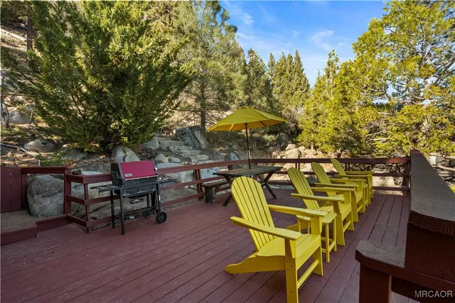 a roof deck with table and chairs a barbeque with wooden floor and fence
