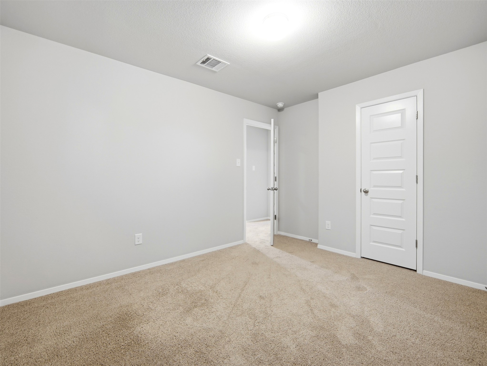 60 Bent Trl Lane Georgetown, TX 78628 - Photo 23 of 40 A spacious, neutral room offers plush carpeting and a clear pathway to another area, perfect for personalization.