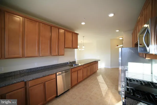 a kitchen with stainless steel appliances granite countertop a sink a stove and a refrigerator
