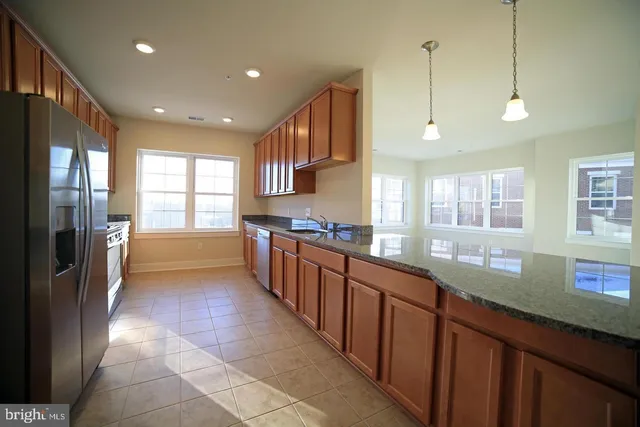 a kitchen with stainless steel appliances granite countertop a sink and a refrigerator
