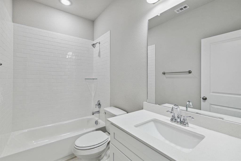 824 Heart Reef Road Plano, TX 75075 - Photo 14 of 19 Bathroom featuring a white subway tile shower surround, a built-in tub, a white vanity with an integrated sink, a large wall-mounted mirror, and overhead lighting