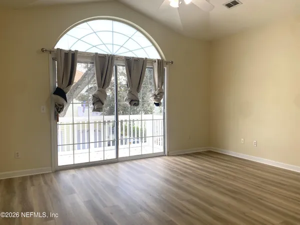 an empty room with wooden floor fan and windows