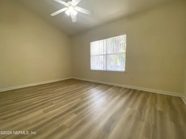 a view of an empty room with wooden floor and a window