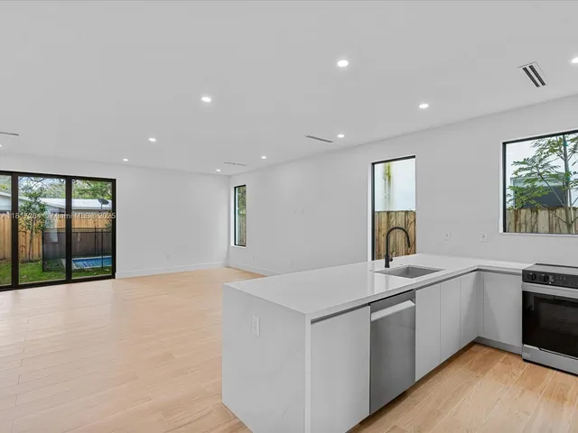 a view of a kitchen counter top space with stainless steel appliances granite countertop a sink and a large window