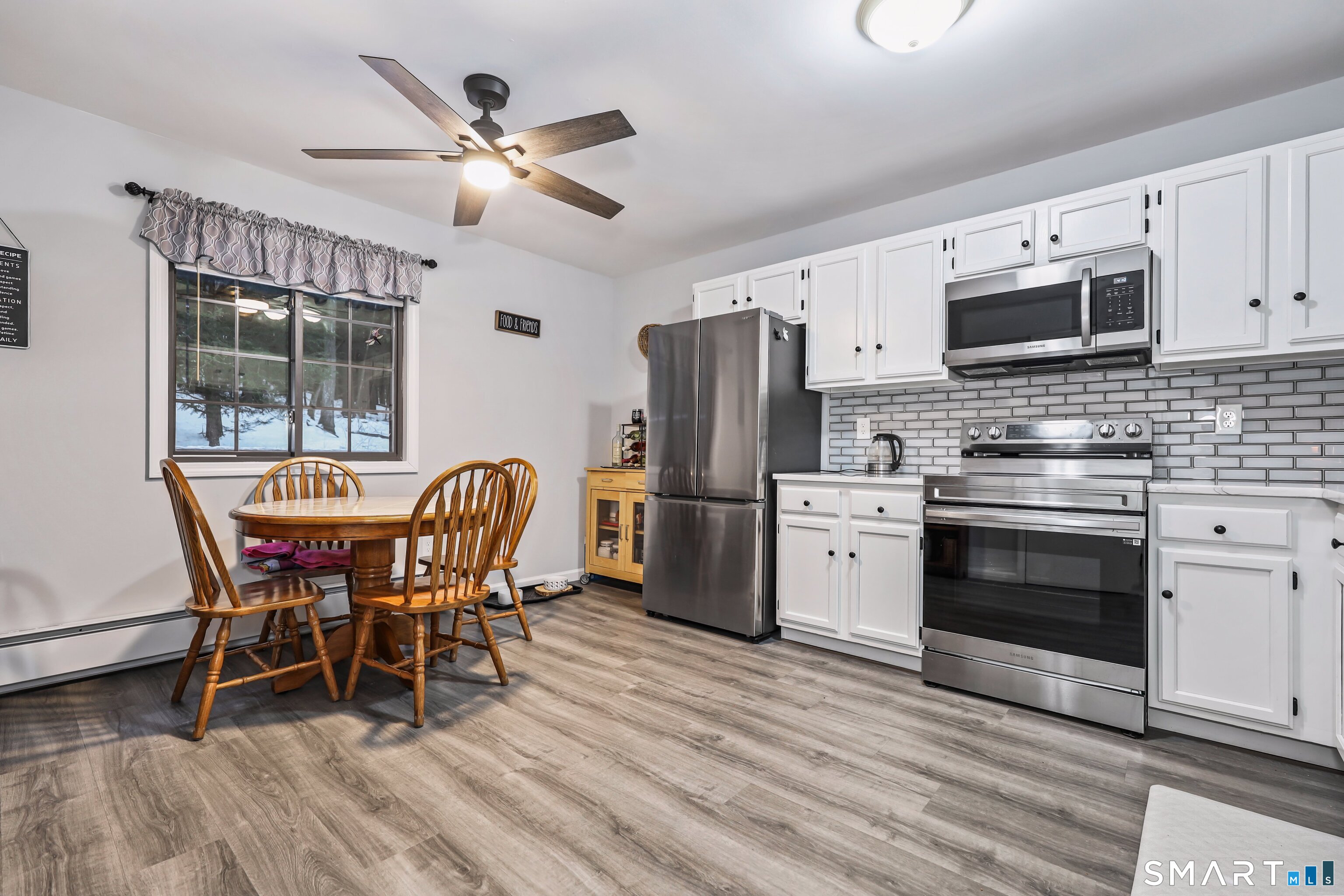 143 Pine Hill Road, Unit 5C Thomaston, CT 06787 - Photo 5 of 29 a kitchen with stainless steel appliances granite countertop a stove a refrigerator a microwave a dining table and chairs with wooden floor