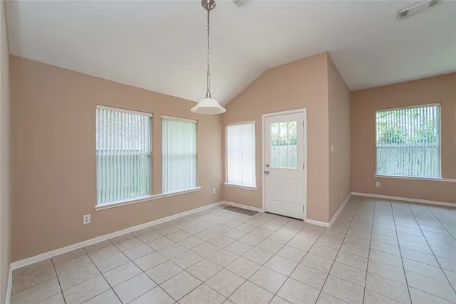 a view of an empty room with window and chandelier fan