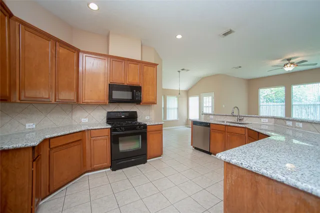 a large kitchen with stainless steel appliances granite countertop a stove a sink and a microwave