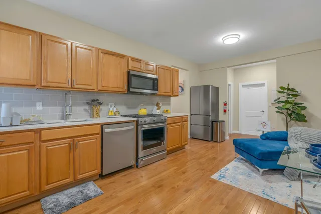 a kitchen with granite countertop a refrigerator a stove a sink cabinets and wooden floor