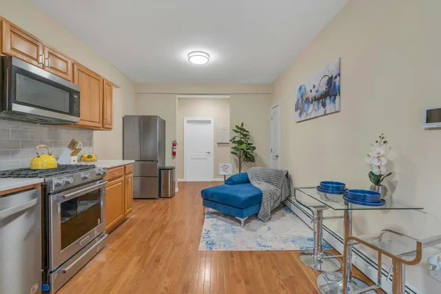 a kitchen with stainless steel appliances granite countertop a refrigerator a stove a sink dishwasher and white cabinets with wooden floor