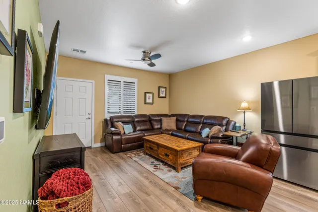 a living room with furniture a flat screen tv and a refrigerator