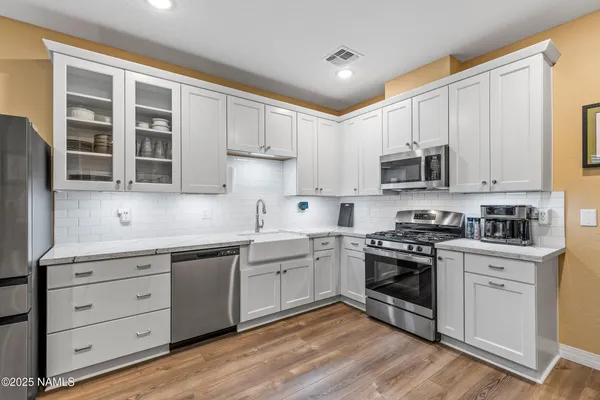 a kitchen with cabinets stainless steel appliances a sink and wooden floor