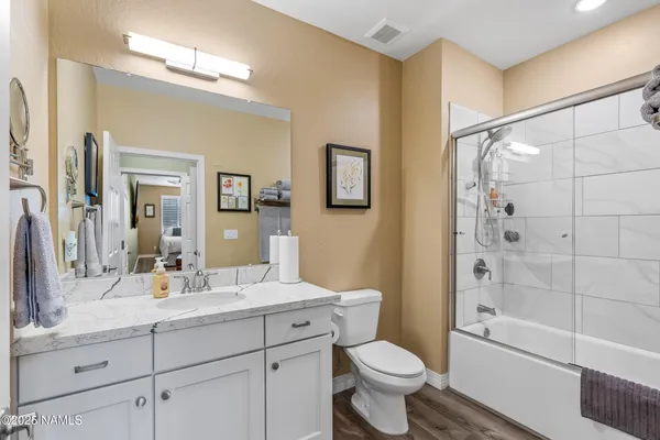 a bathroom with a bathtub shower sink vanity mirror and toilet