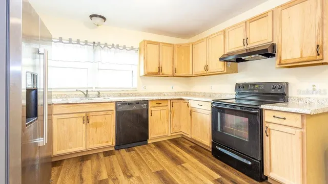 a kitchen with stainless steel appliances granite countertop a stove a sink and a microwave